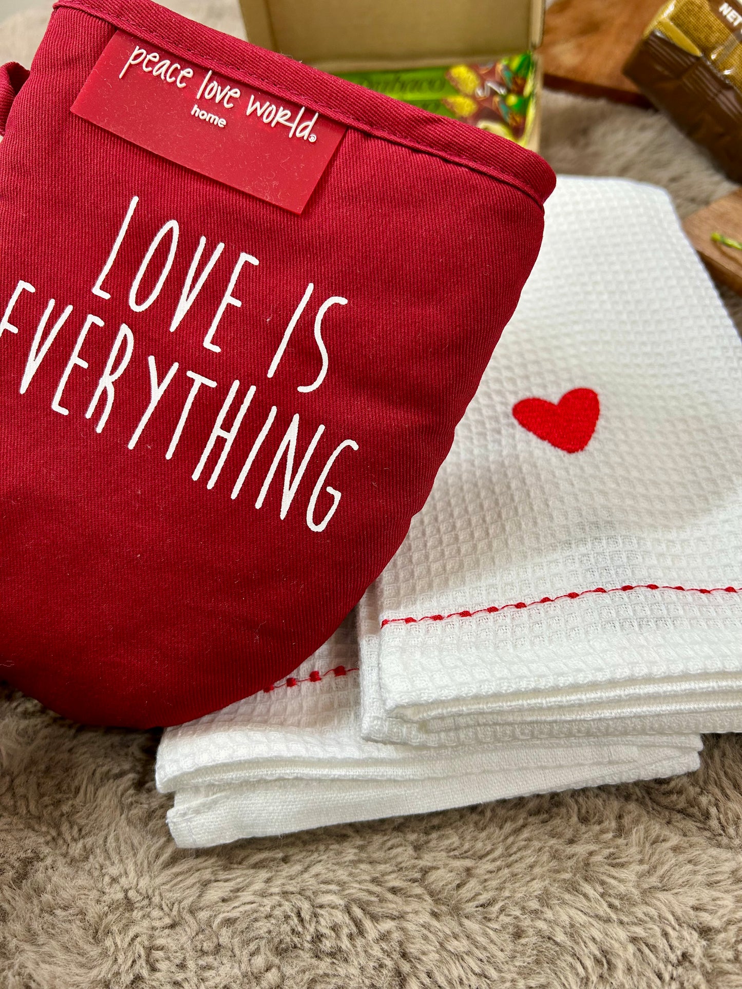 Red towel with 'LOVE IS EVERYTHING' text and a white towel with a red heart on a textured surface.