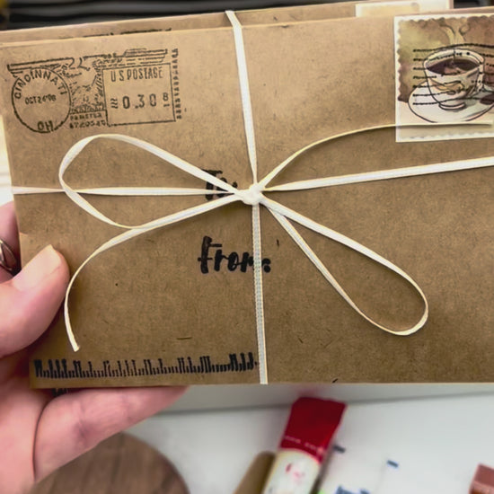 Video showing the assembly of the Week of Coffee Breaks Gift Box with the envelope bundle being placed inside, followed by a full view of the coffee gift box and ending with a disposable cup being filled with fresh coffee